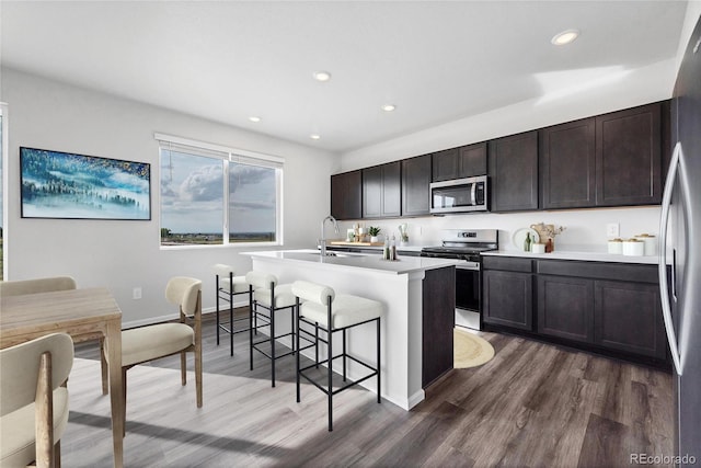 2705 73rd Avenue Ct, Greeley, CO 80634 - kitchen featuring appliances with stainless steel finishes, dark wood finished floors, a kitchen bar, recessed lighting, and a center island with sink