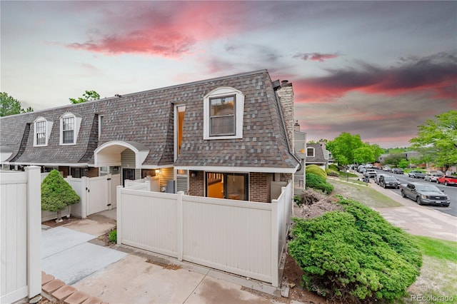 15491 E Wyoming Dr Unit A, Aurora, CO 80017 - view of front of house with brick siding, mansard roof, a gate, a fenced front yard, and a shingled roof