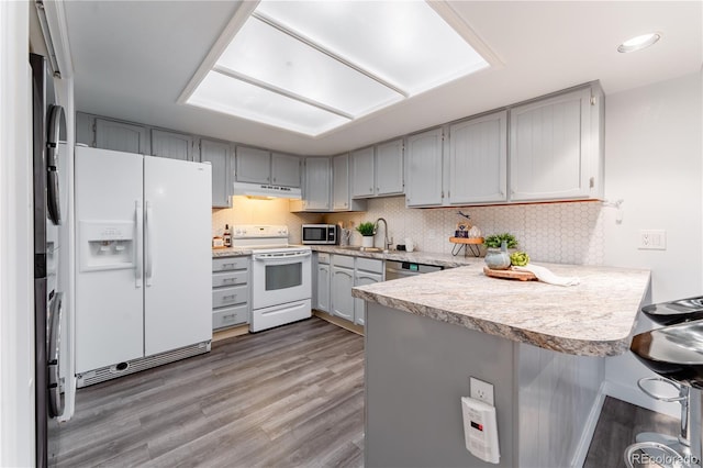 15491 E Wyoming Dr Unit A, Aurora, CO 80017 - kitchen with white appliances, under cabinet range hood, a peninsula, gray cabinets, and recessed lighting