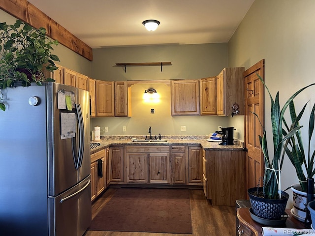 kitchen featuring stone countertops, sink, stainless steel fridge, and dark hardwood / wood-style floors