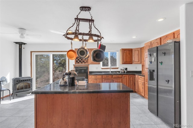 kitchen with a wood stove, stainless steel refrigerator with ice dispenser, plenty of natural light, and a kitchen island