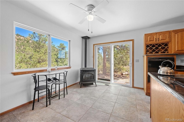 tiled dining area featuring a wood stove and ceiling fan