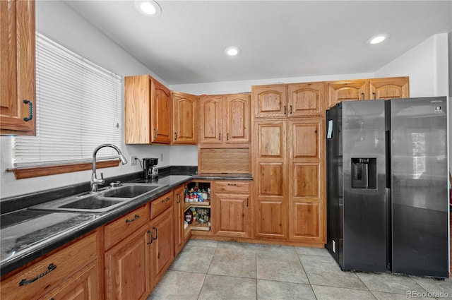 kitchen featuring sink, stainless steel fridge, light tile patterned flooring, and dark stone counters