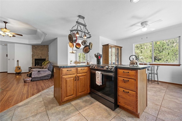 kitchen with black electric range, a center island, light hardwood / wood-style flooring, and a large fireplace