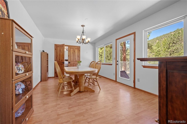 dining area featuring light hardwood / wood-style flooring, a wealth of natural light, and an inviting chandelier