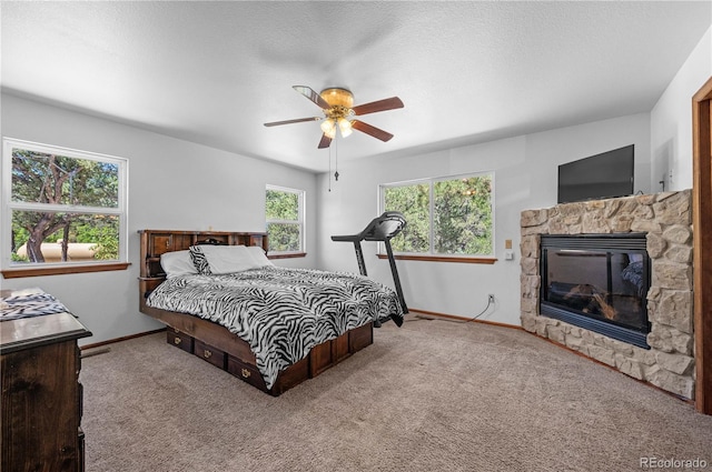 bedroom with a textured ceiling, a fireplace, carpet flooring, and ceiling fan