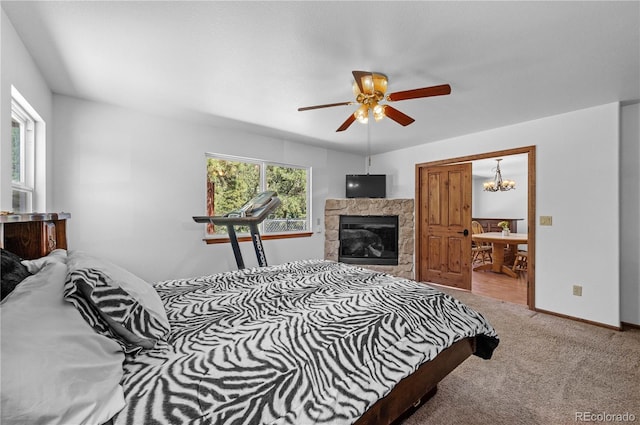 carpeted bedroom with ensuite bathroom, a tiled fireplace, and ceiling fan