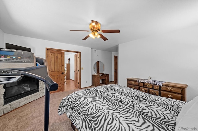 carpeted bedroom featuring ceiling fan and a fireplace