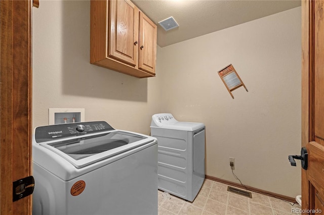 laundry area with washer and dryer, a textured ceiling, and cabinets