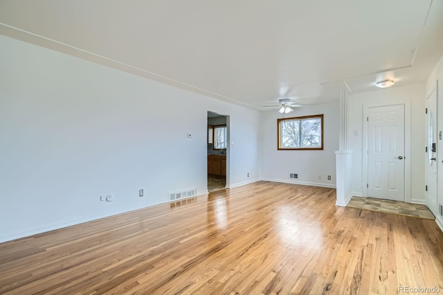 interior space featuring baseboards, a ceiling fan, visible vents, and light wood-type flooring