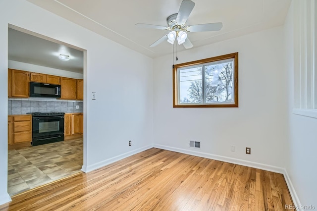 interior space with baseboards, decorative backsplash, visible vents, black appliances, and brown cabinetry
