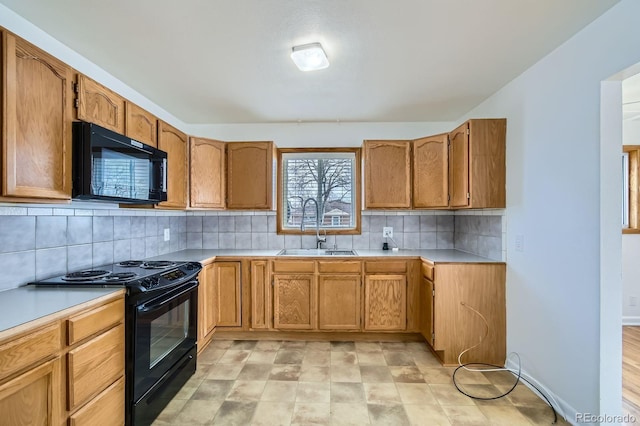 kitchen featuring light countertops, tasteful backsplash, a sink, black appliances, and brown cabinetry
