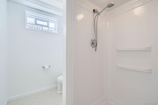 bathroom featuring toilet, a shower, and baseboards