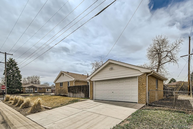 view of property exterior with brick siding, an outbuilding, driveway, and fence