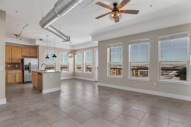 kitchen with a center island with sink, ceiling fan, stainless steel appliances, decorative light fixtures, and sink