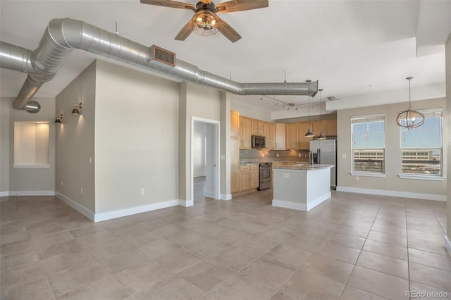 kitchen with decorative light fixtures, ceiling fan with notable chandelier, stainless steel appliances, and a kitchen island