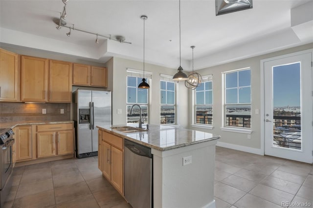 kitchen featuring an island with sink, stainless steel appliances, decorative backsplash, a tray ceiling, and sink