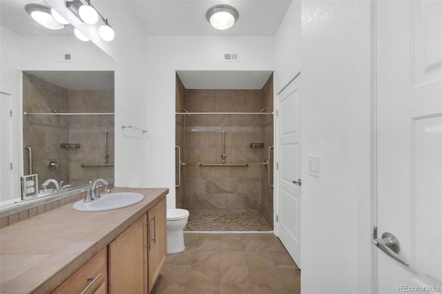 bathroom with toilet, vanity, tile patterned flooring, and a tile shower