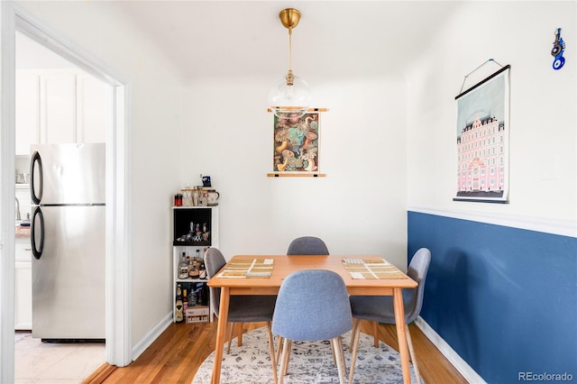 dining space featuring light wood-style flooring and baseboards