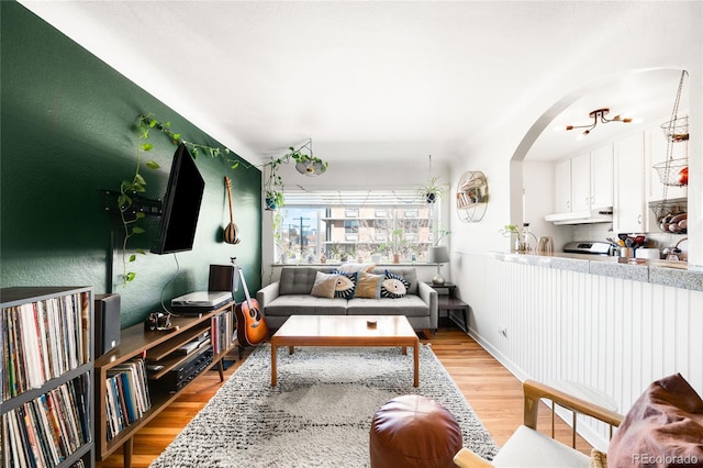 living room featuring light wood-type flooring and arched walkways