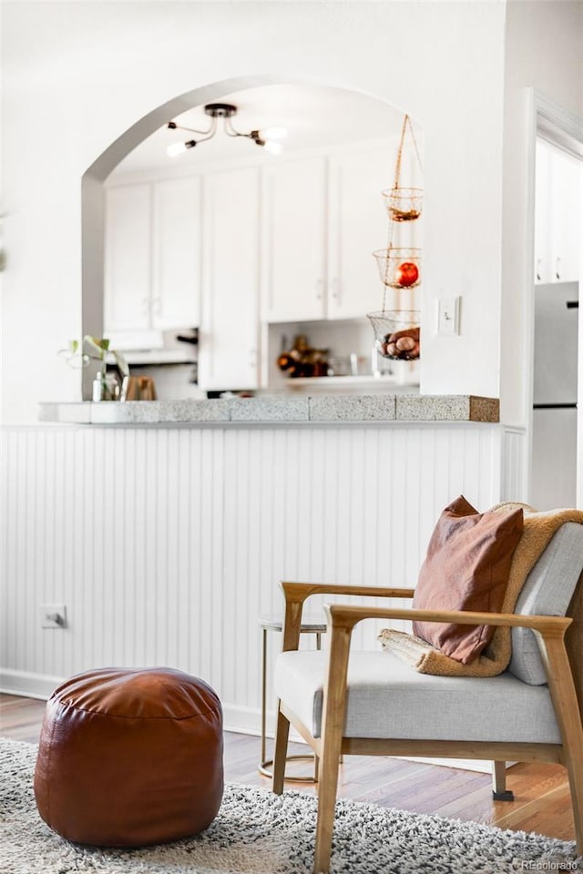 interior space featuring a wainscoted wall, freestanding refrigerator, and wood finished floors