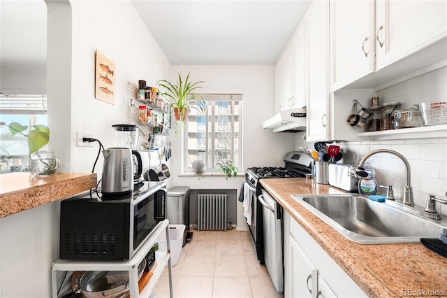 kitchen featuring a sink, under cabinet range hood, backsplash, stainless steel appliances, and radiator