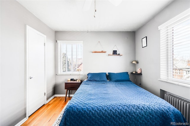 bedroom featuring baseboards, radiator, ceiling fan, and light wood finished floors