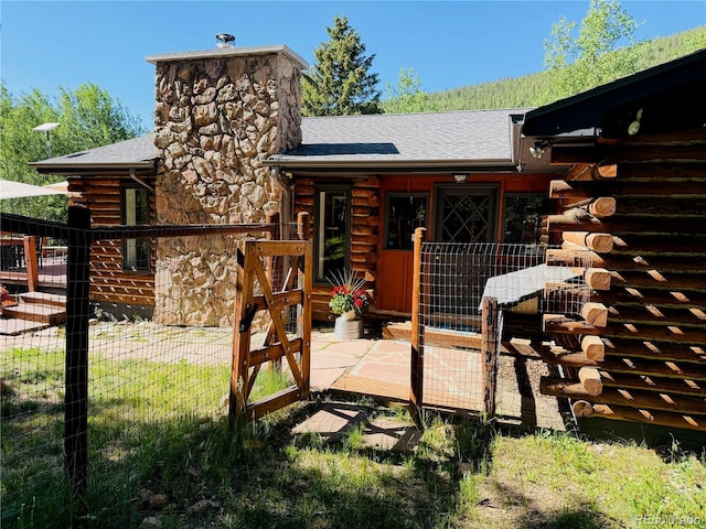 10439 Christopher Dr, Conifer, CO 80433 - back of house with log siding, a chimney, roof with shingles, and stone siding
