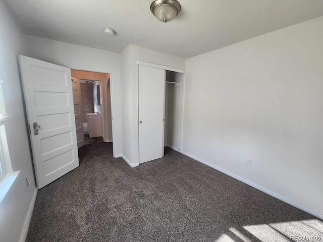 unfurnished bedroom featuring dark carpet and a closet