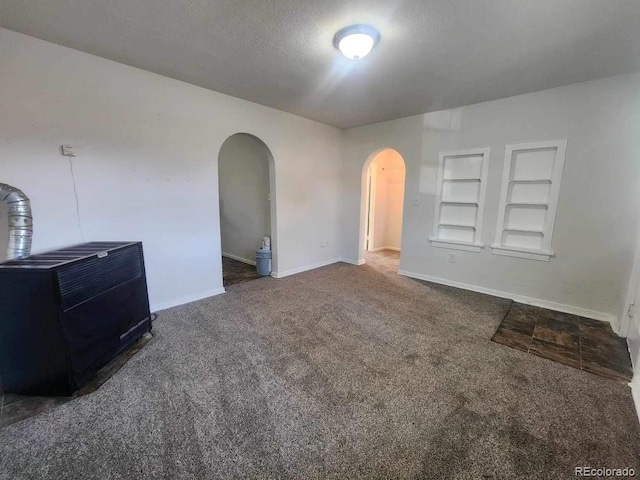 interior space featuring dark carpet, a textured ceiling, and built in features