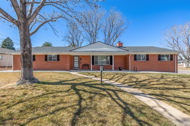 ranch-style house featuring brick siding, a chimney, a front lawn, and roof with shingles