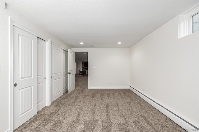 interior space featuring multiple closets, recessed lighting, carpet floors, a baseboard radiator, and baseboards