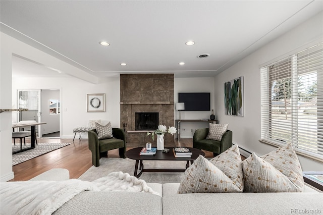 living room with a baseboard heating unit, recessed lighting, wood finished floors, and baseboards