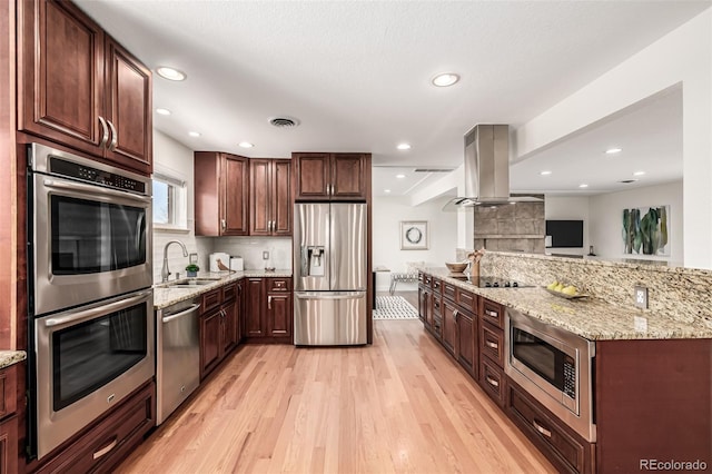 kitchen featuring visible vents, light wood-style flooring, a sink, stainless steel appliances, and island range hood