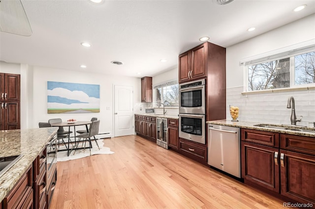 kitchen with wine cooler, light wood finished floors, stainless steel appliances, and a sink