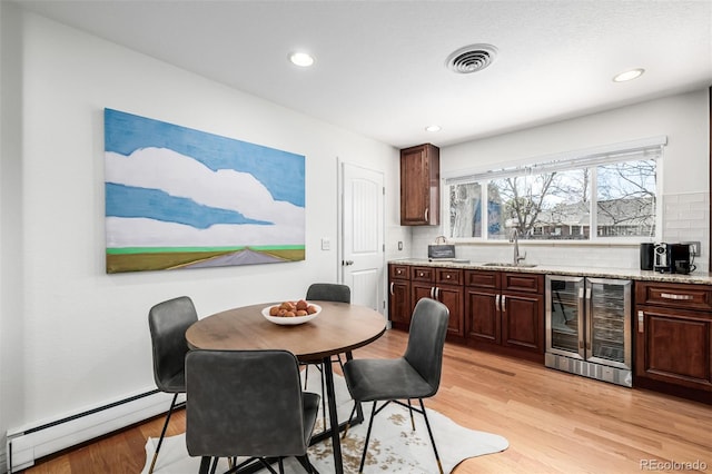 dining space with light wood finished floors, visible vents, wine cooler, recessed lighting, and a baseboard radiator