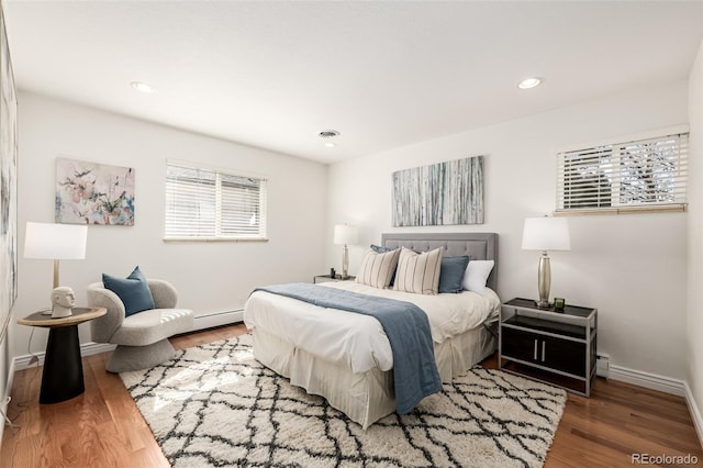 bedroom with wood finished floors, visible vents, baseboards, a baseboard radiator, and recessed lighting