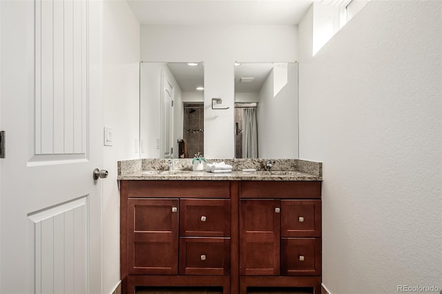 full bathroom with double vanity, a shower stall, and a sink