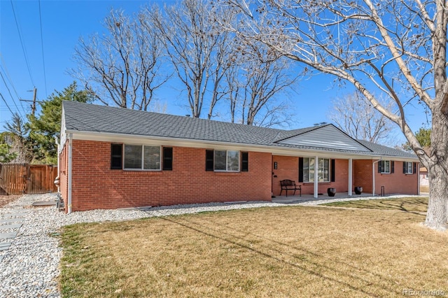 single story home with brick siding, a shingled roof, fence, a front yard, and a patio area