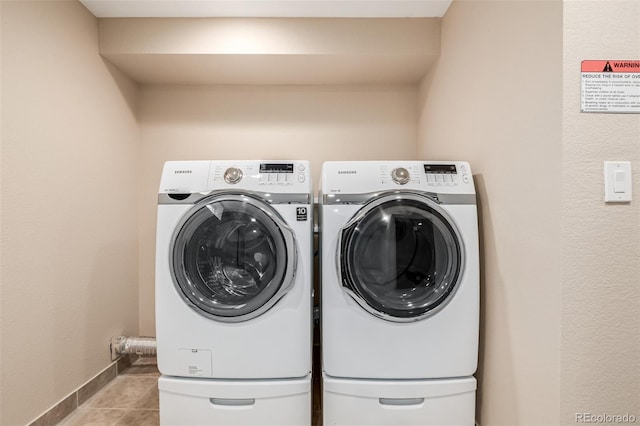 washroom featuring tile patterned floors, laundry area, baseboards, and separate washer and dryer