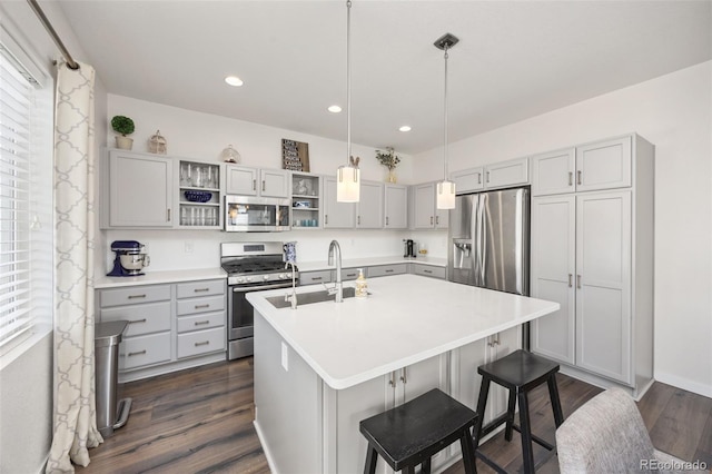 kitchen featuring a sink, open shelves, stainless steel appliances, a kitchen island with sink, and light countertops