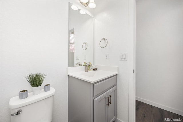 bathroom with toilet, baseboards, wood finished floors, and vanity