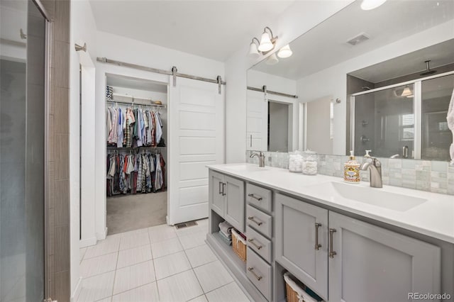full bathroom with a sink, double vanity, a shower stall, and tile patterned floors