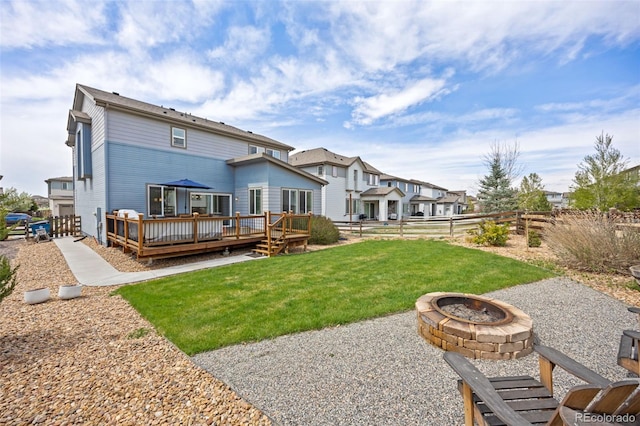 back of house with a yard, an outdoor fire pit, fence, and a deck