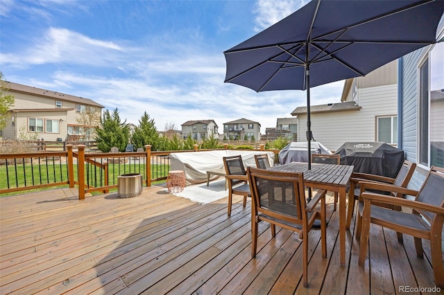wooden terrace featuring a residential view, outdoor dining space, and grilling area