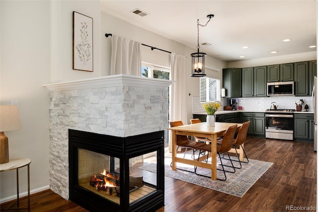 4963 Collingswood Dr, Highlands Ranch, CO 80130 - kitchen with appliances with stainless steel finishes, green cabinetry, backsplash, dark wood-style floors, and hanging light fixtures