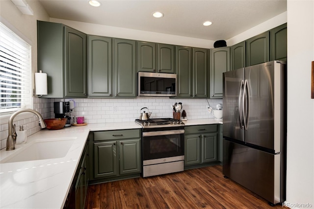 4963 Collingswood Dr, Highlands Ranch, CO 80130 - kitchen featuring appliances with stainless steel finishes, a sink, green cabinetry, backsplash, and recessed lighting