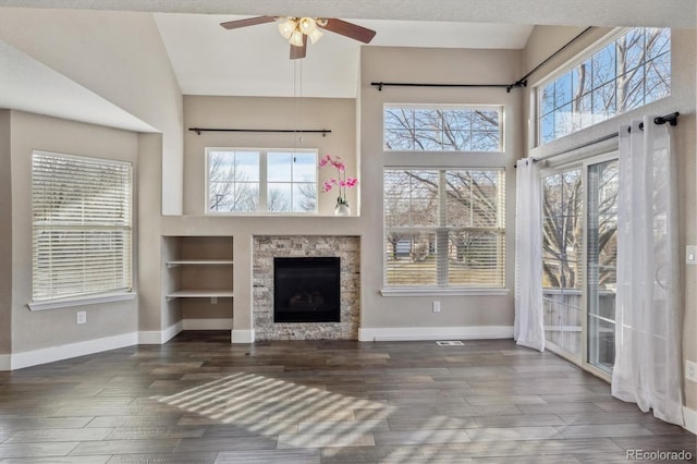 unfurnished living room featuring wood finished floors, baseboards, and a wealth of natural light