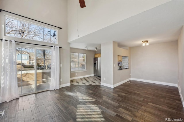 interior space with visible vents, baseboards, dark wood finished floors, rail lighting, and a high ceiling