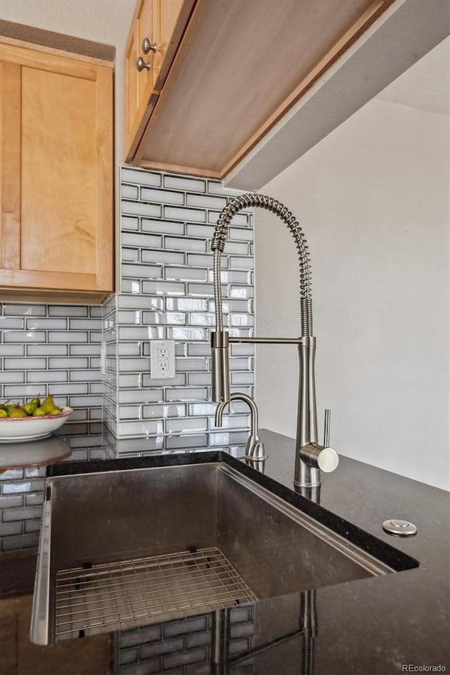 details with a sink, backsplash, dark stone countertops, and light brown cabinets